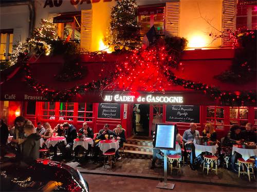 Customers sitting at a Paris cafe at night